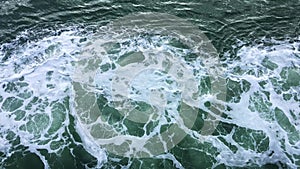 Waves and white foam spray created by powerful ferry boat moving across the sea.