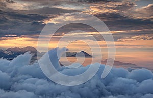 Waving clouds and jagged mountains in red glowing autumn mist