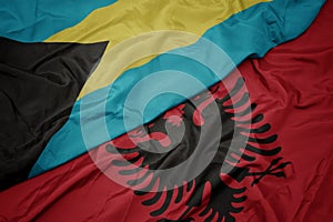 waving colorful flag of albania and national flag of bahamas