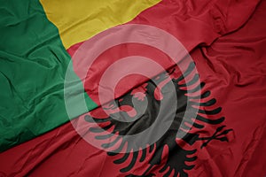 waving colorful flag of albania and national flag of benin
