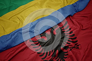 waving colorful flag of albania and national flag of gabon