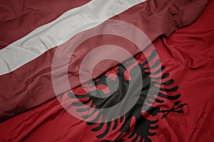 waving colorful flag of albania and national flag of latvia