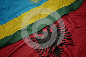 waving colorful flag of albania and national flag of rwanda