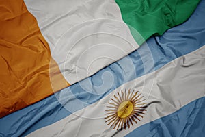 waving colorful flag of argentina and national flag of cote divoire