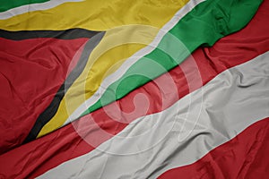 waving colorful flag of austria and national flag of guyana