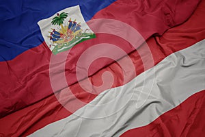 waving colorful flag of austria and national flag of haiti