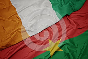 waving colorful flag of burkina faso and national flag of cote divoire