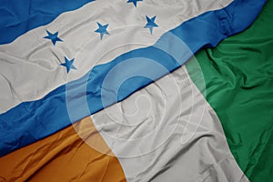 Waving colorful flag of cote divoire and national flag of honduras