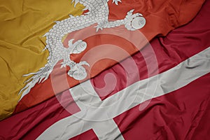 waving colorful flag of denmark and national flag of bhutan