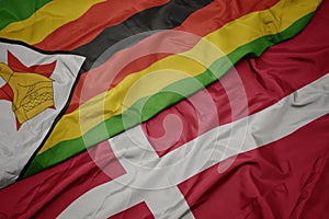 waving colorful flag of denmark and national flag of zimbabwe