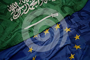 waving colorful flag of european union and flag of saudi arabia on a euro money banknotes background. finance concept