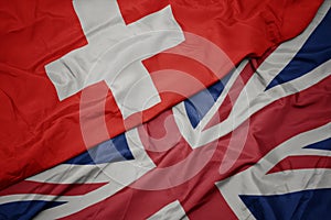 waving colorful flag of great britain and national flag of switzerland