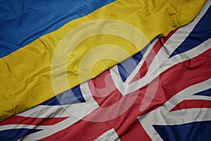 waving colorful flag of great britain and national flag of ukraine