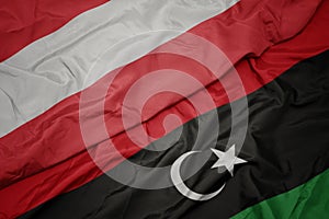 waving colorful flag of libya and national flag of austria