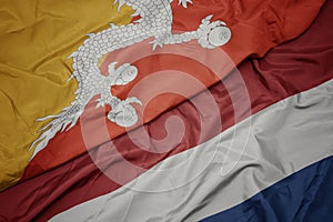waving colorful flag of netherlands and national flag of bhutan
