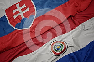 Waving colorful flag of paraguay and national flag of slovakia