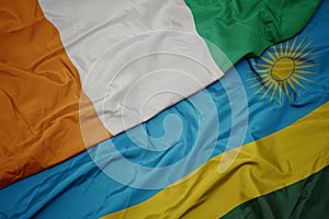 waving colorful flag of rwanda and national flag of cote divoire