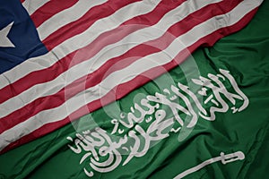 waving colorful flag of saudi arabia and national flag of liberia