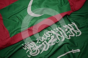 waving colorful flag of saudi arabia and national flag of maldives