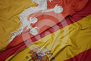 waving colorful flag of spain and national flag of bhutan