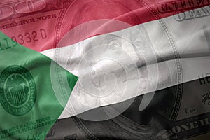 waving colorful flag of sudan on a american dollar money background. finance concept