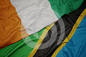 waving colorful flag of tanzania and national flag of cote divoire