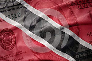 waving colorful flag of trinidad and tobago on a american dollar money background. finance concept