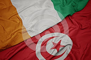 waving colorful flag of tunisia and national flag of cote divoire