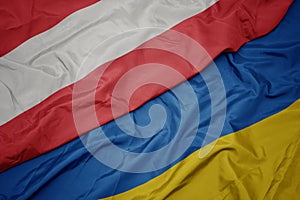 waving colorful flag of ukraine and national flag of austria