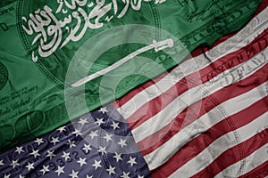waving colorful flag of united states of america and national flag of saudi arabia on the dollar money background. finance concept