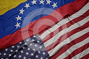 waving colorful flag of united states of america and national flag of venezuela