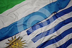 waving colorful flag of uruguay and national flag of sierra leone