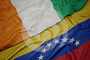 waving colorful flag of venezuela and national flag of cote divoire