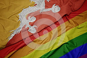 waving colorful gay rainbow flag and national flag of bhutan