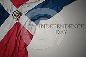 waving colorful national flag of dominican republic on a gray background with text independence day