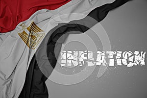 waving colorful national flag of egypt on a gray background with broken text inflation. 3d illustration