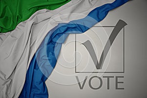 Waving colorful national flag of sierra leone on a gray background with text vote. 3D illustration