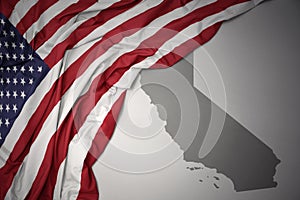 Waving national flag of united states of america on a gray california state map background.