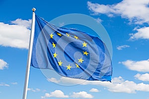 Waving European Union flag against blue sky background.