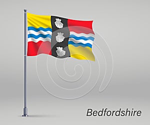 Waving flag of Bedfordshire - county of England on flagpole. Tem