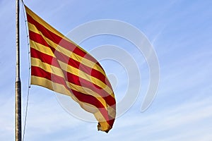 Waving flag of the Catalunya Catalonia on background of the blue sky. . Catalonia flag waving against clear blue sky.