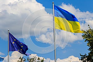Waving flag of European Union and flag of Ukraine against blue sky