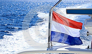 Waving flag of Holland on the stern of a yacht traveling in the waters of the Aegean sea in Greece