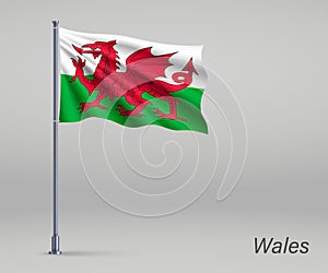 Waving flag of Wales - territory of United Kingdom on flagpole