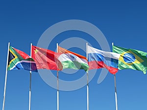 Waving flags of the BRICS countries against the blue sky