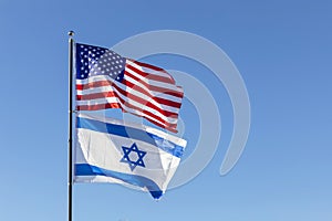 Waving Flags Of USA And Israel On The Same Flagpole On Background Of Blue Sky. Copy Space