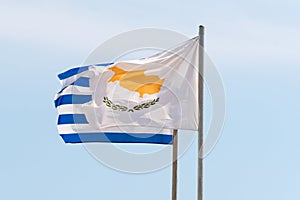 Waving Greek and Cyprian flags agaist the blue sky in strong wind