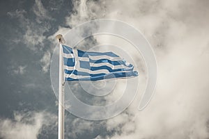 Waving Greek flag against a blue sky with clouds