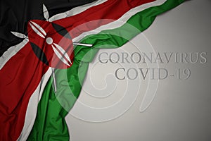 waving national flag of kenya on a gray background with text coronavirus covid-19 . concept