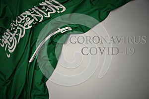 Waving national flag of saudi arabia on a gray background with text coronavirus covid-19 . concept